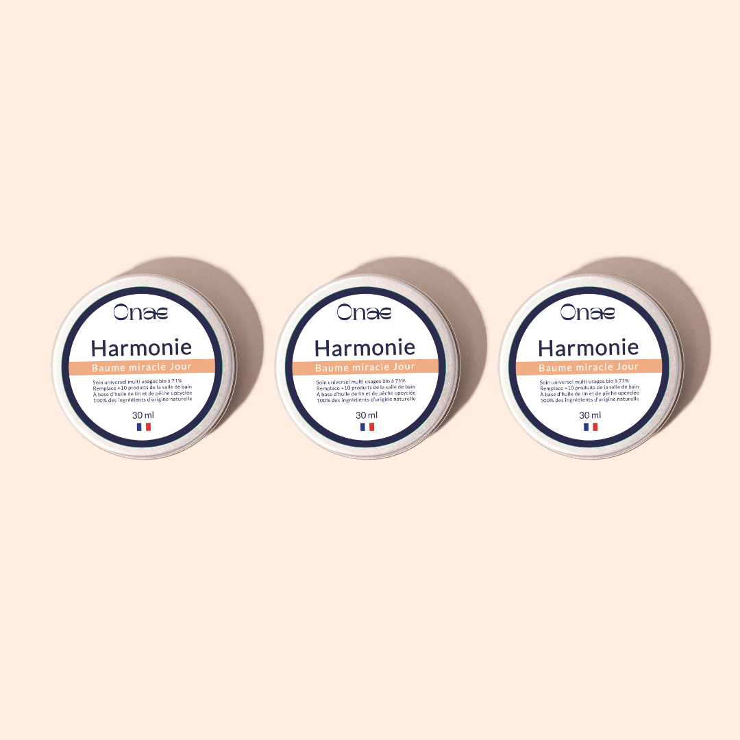 Trois pots identiques de baume visage hydratant en format 30 ml, avec étiquette blanche et orange, sur fond beige clair, illustrant un soin concentré en actifs réparateurs pour la peau.