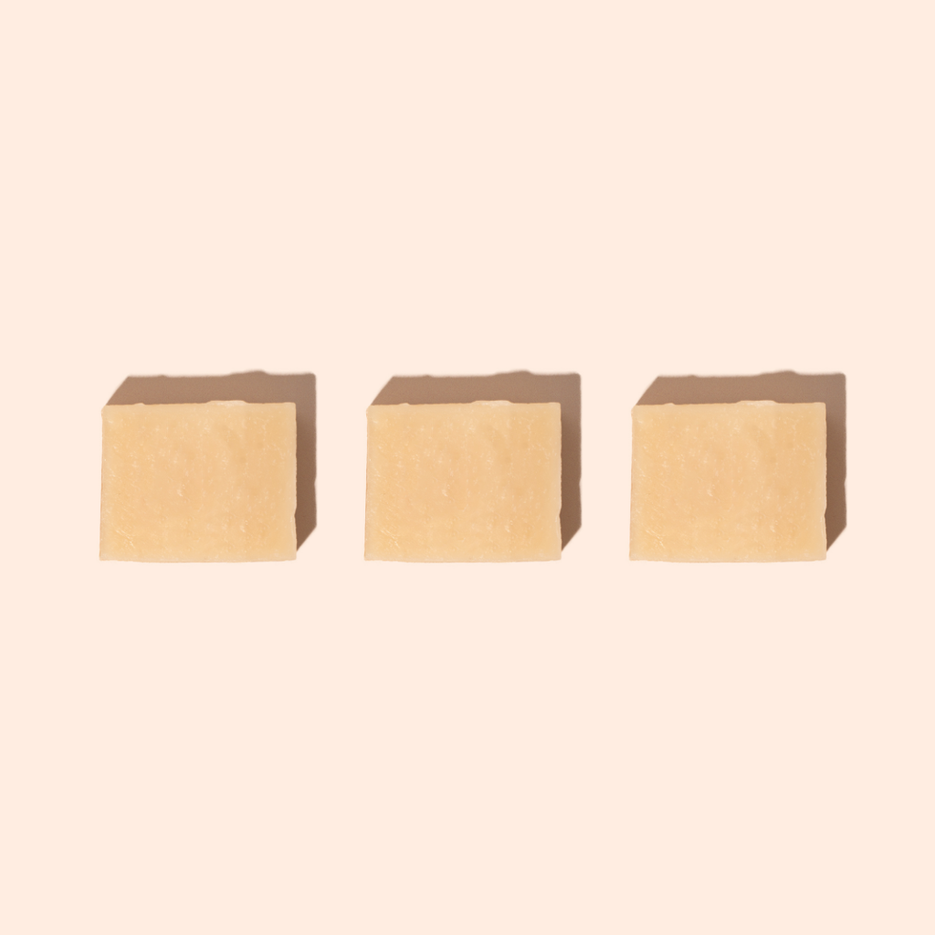 Trois savons beige clair disposés en ligne sur fond beige, formulés avec du lait de chèvre et de la sève de bouleau pour une peau renouvelée et apaisée.