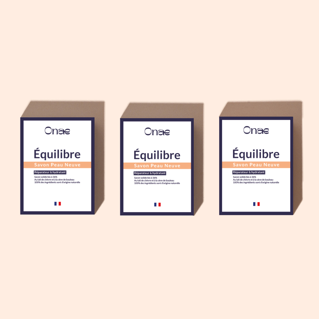 Trois emballages de savon Équilibre avec indication de propriétés réparatrices et hydratantes, soulignant l’utilisation de lait de chèvre et de sève de bouleau dans une présentation sobre.
